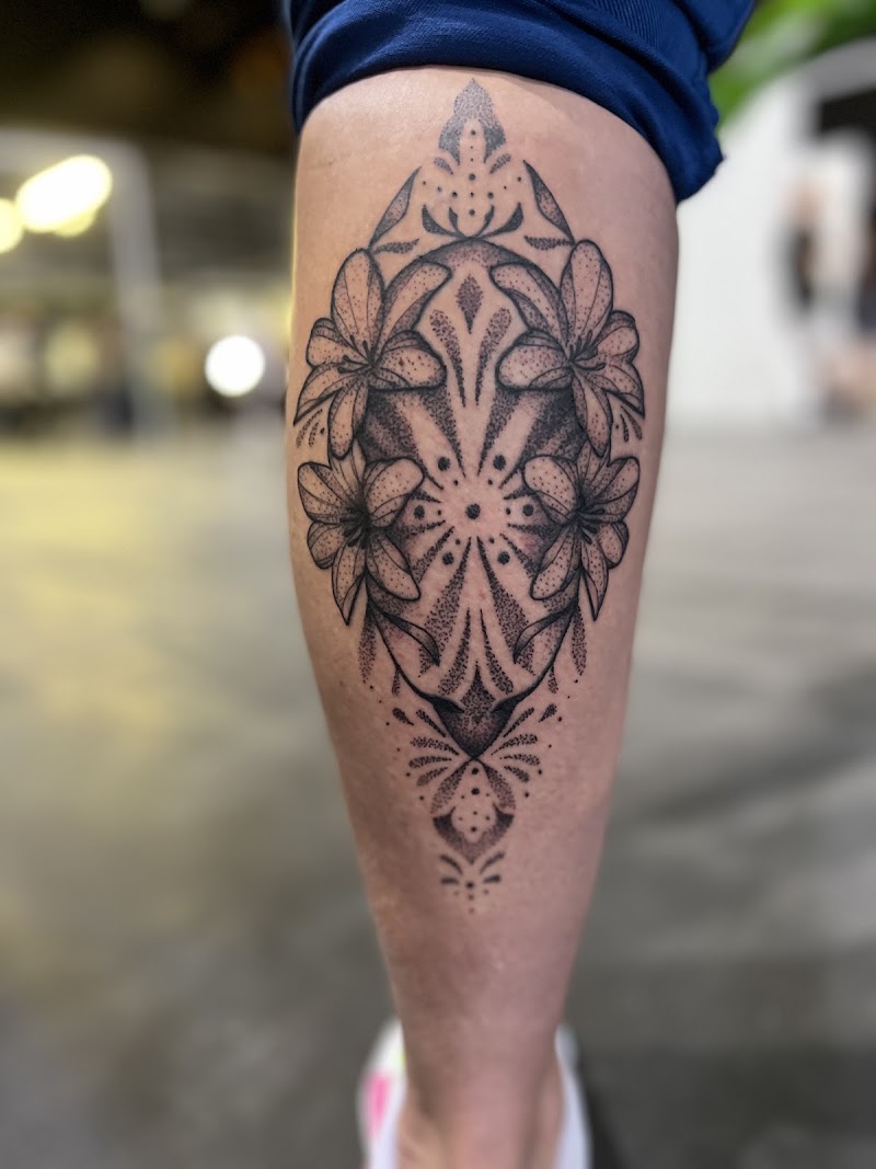 Symmetrische dotwork lelie tattoo op onderbeen.