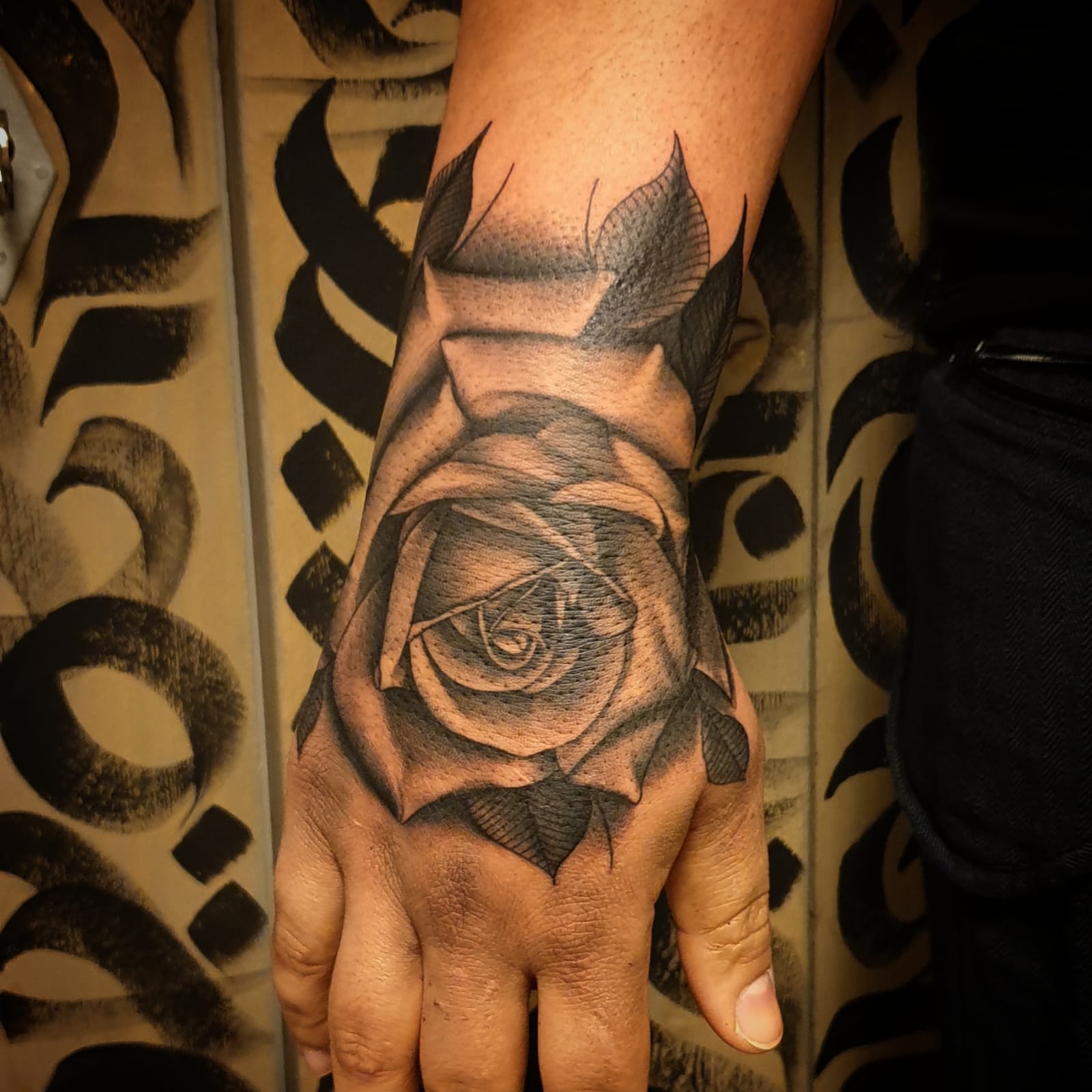 Realistische roos tattoo op de hand in zwart-wit.