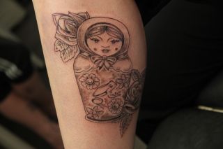 Blackwork matryoshka pop met bloemen op onderbeen.
