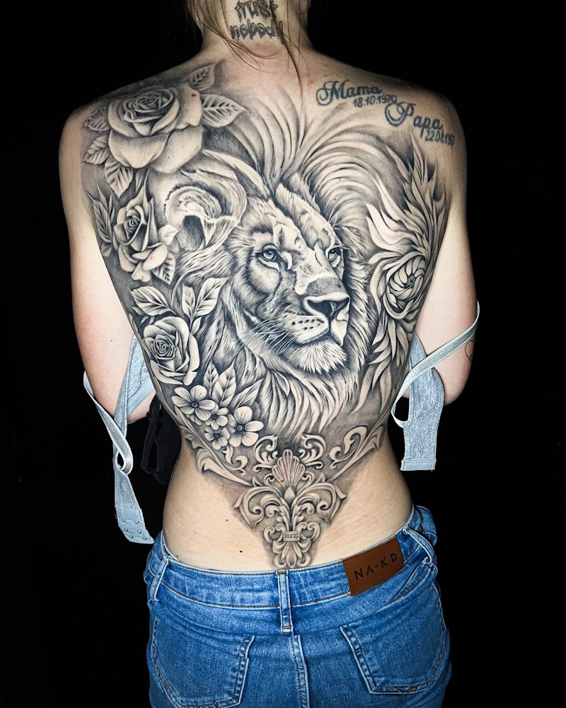 Grote zwart-wit rugtattoo van een leeuw met rozen en een ornament.