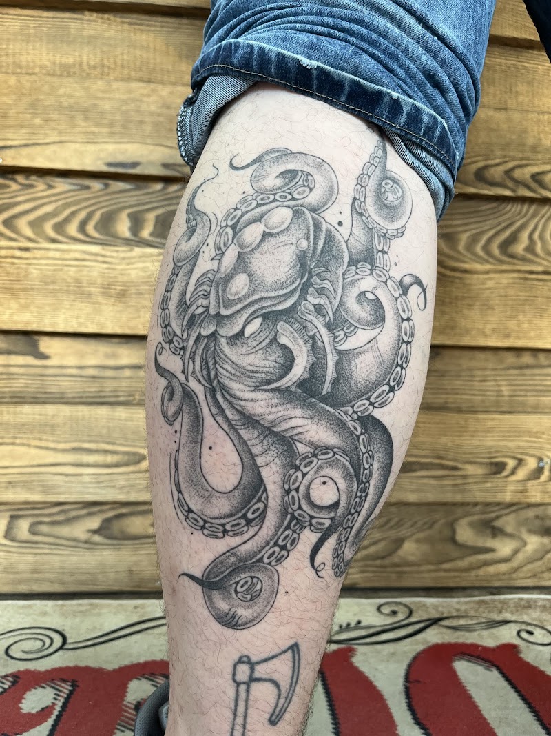 Zwart-wit octopus tattoo op kuit met dotwork en lijnwerk.