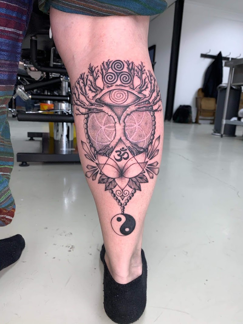 Spirituele tattoo met levensboom, oog, Om, yin yang en geometrie op kuit.