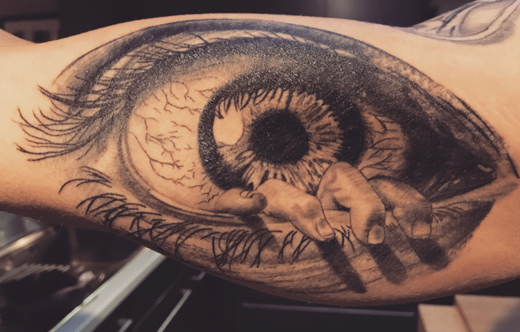 Realistisch oog met hand die eruit komt op bovenarm.