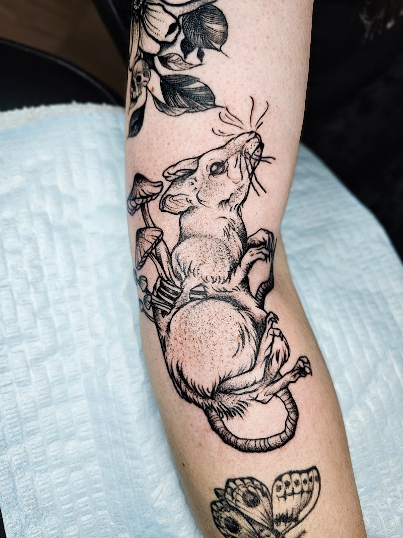 Illustratieve blackwork tattoo van een rat met paddenstoelen op zijn rug.