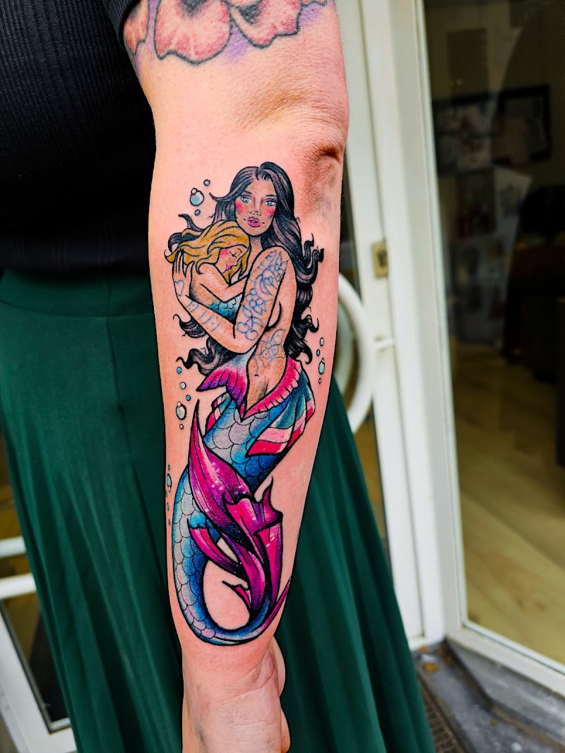 Kleurrijke zeemeermin die een kind omhelst op de onderarm.