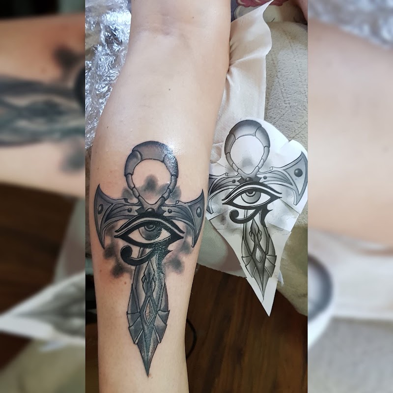 Zwart-wit tattoo van een Ankh kruis met het Oog van Horus op het onderbeen.