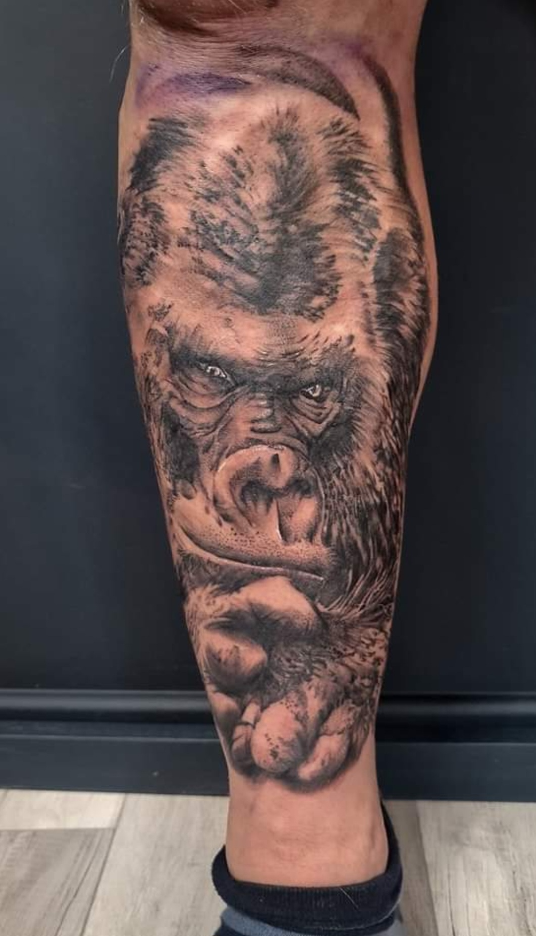 Realistische gorilla tattoo op onderbeen, zwart-wit.