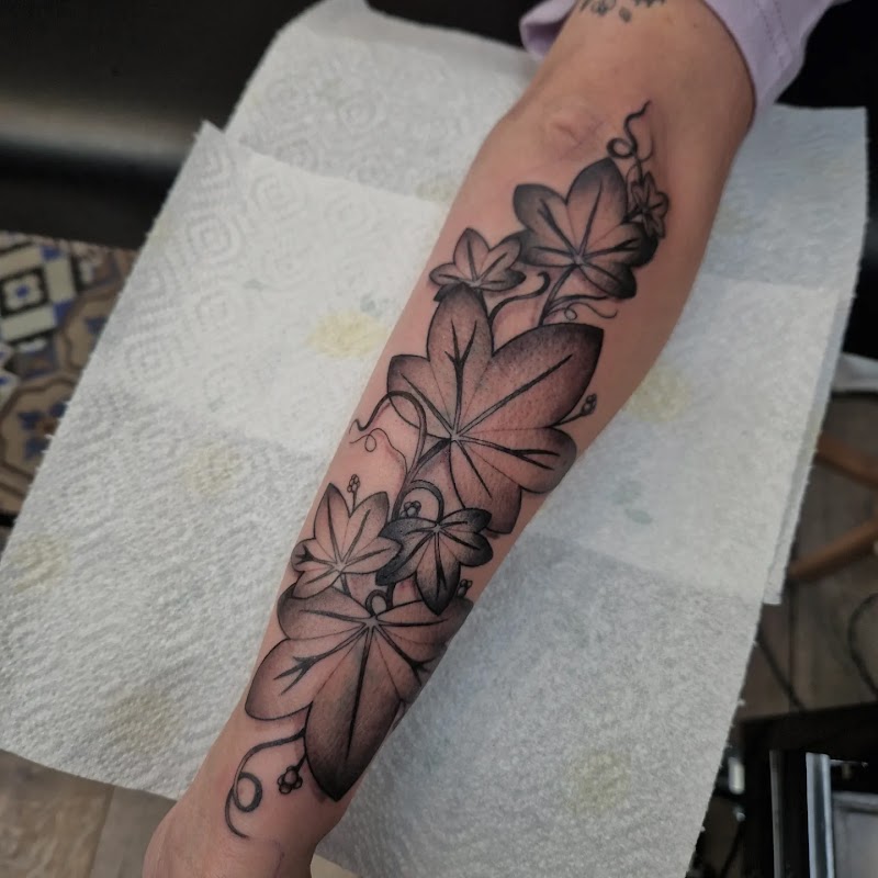 Blackwork tattoo van klimop bladeren op de onderarm.