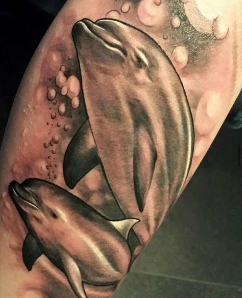 Realistische tattoo van twee zwemmende dolfijnen met luchtbellen.