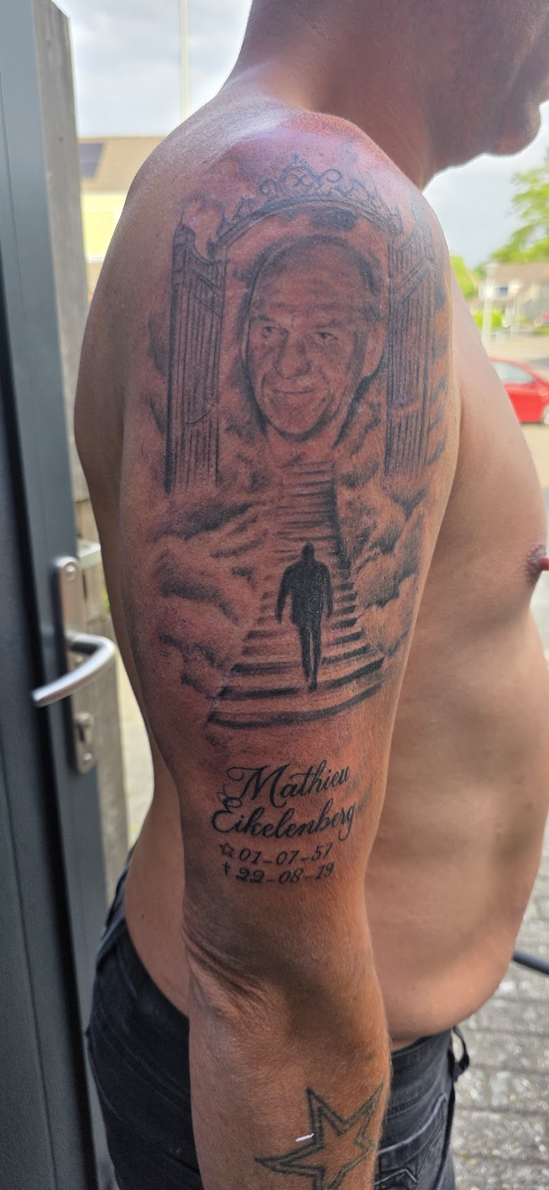 Herdenkingstattoo met portret, hemelpoort en trap op bovenarm.
