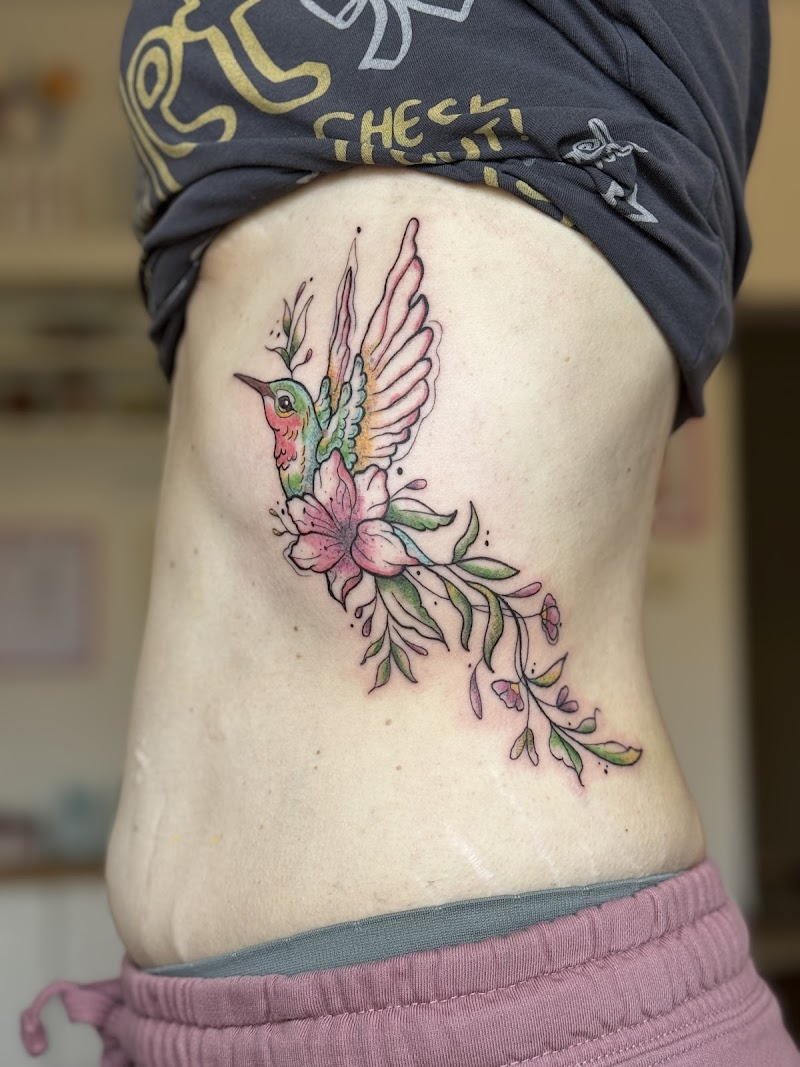 Kleurrijke kolibrie met bloemen en bladeren op de ribben.