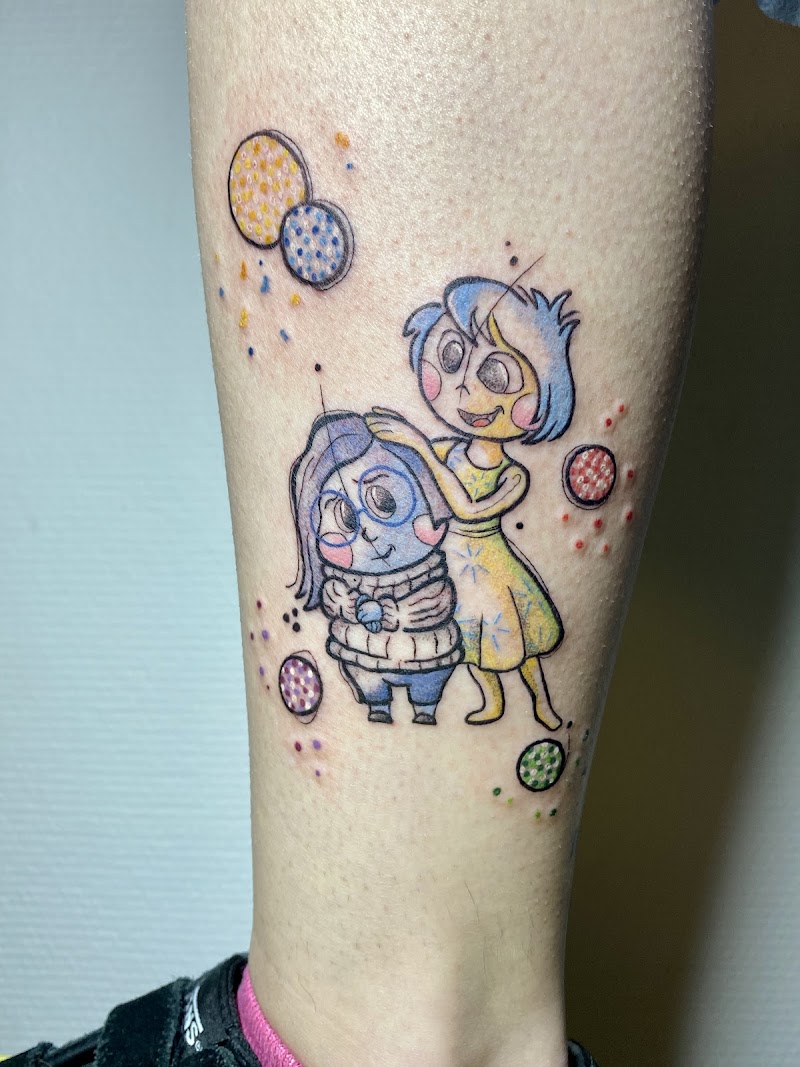 Kleurrijke tattoo van Joy en Sadness uit Inside Out op onderbeen.
