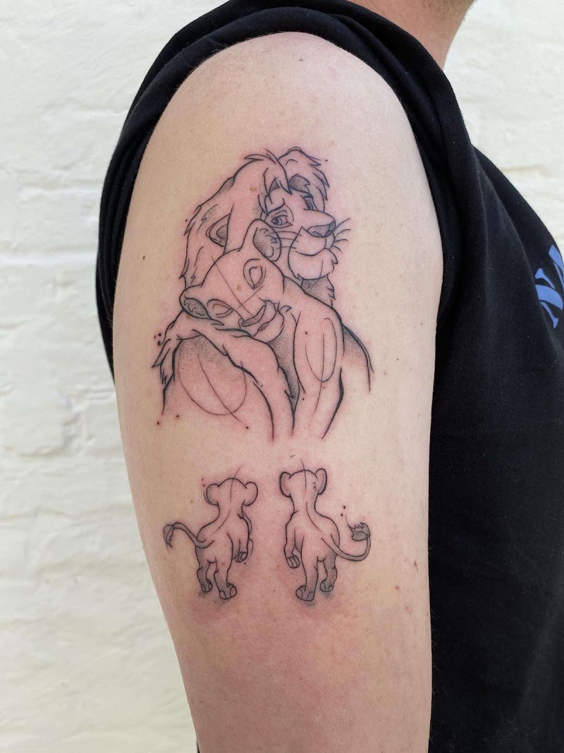 Fineline tattoo van Simba en Nala knuffelend, met twee welpjes eronder.