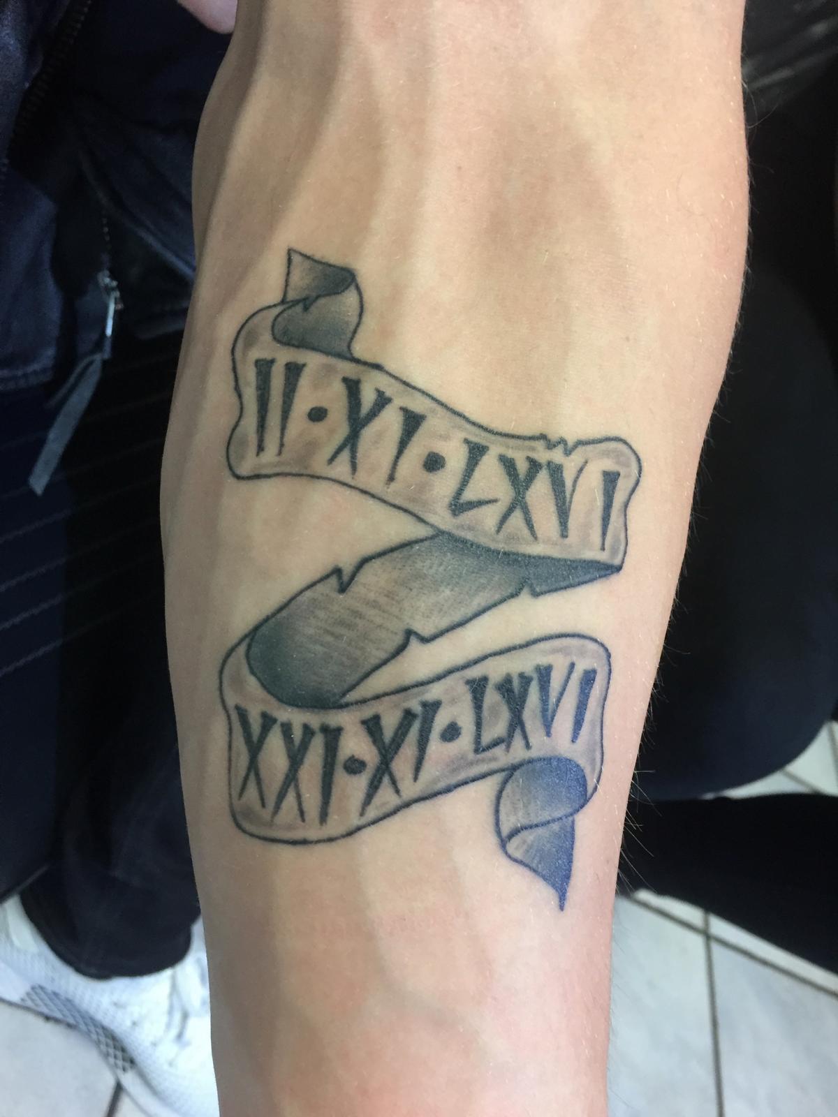 Banier met Romeinse cijfers II-XI-LXVI en XXI-XI-LXVI op onderarm.