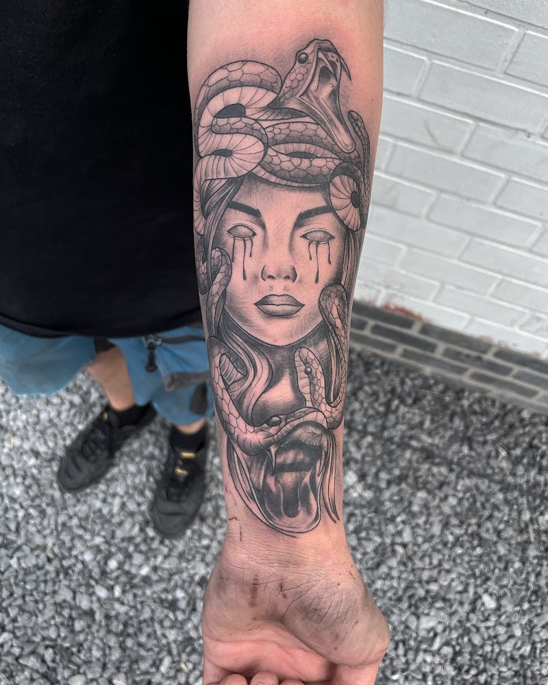 Zwart-wit Medusa tattoo met slangenhaar en tranen op onderarm.