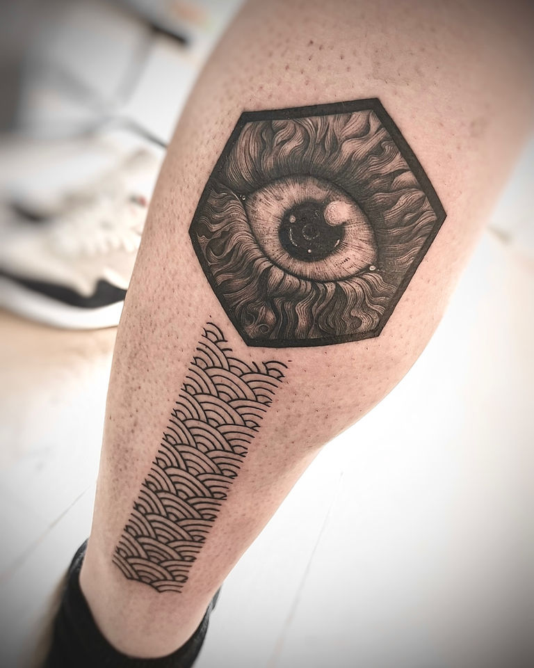 Blackwork oog in zeshoek met Japans golfpatroon op onderbeen.