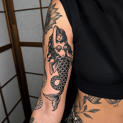 Traditionele zeemeermin tattoo op bovenarm.