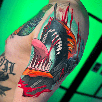 Kleurrijke Chainsaw Man tattoo op bovenarm, met bloed en tanden.