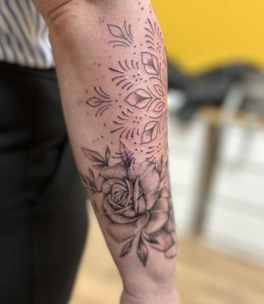 Blackwork tattoo op onderarm met een mandala en een roos.