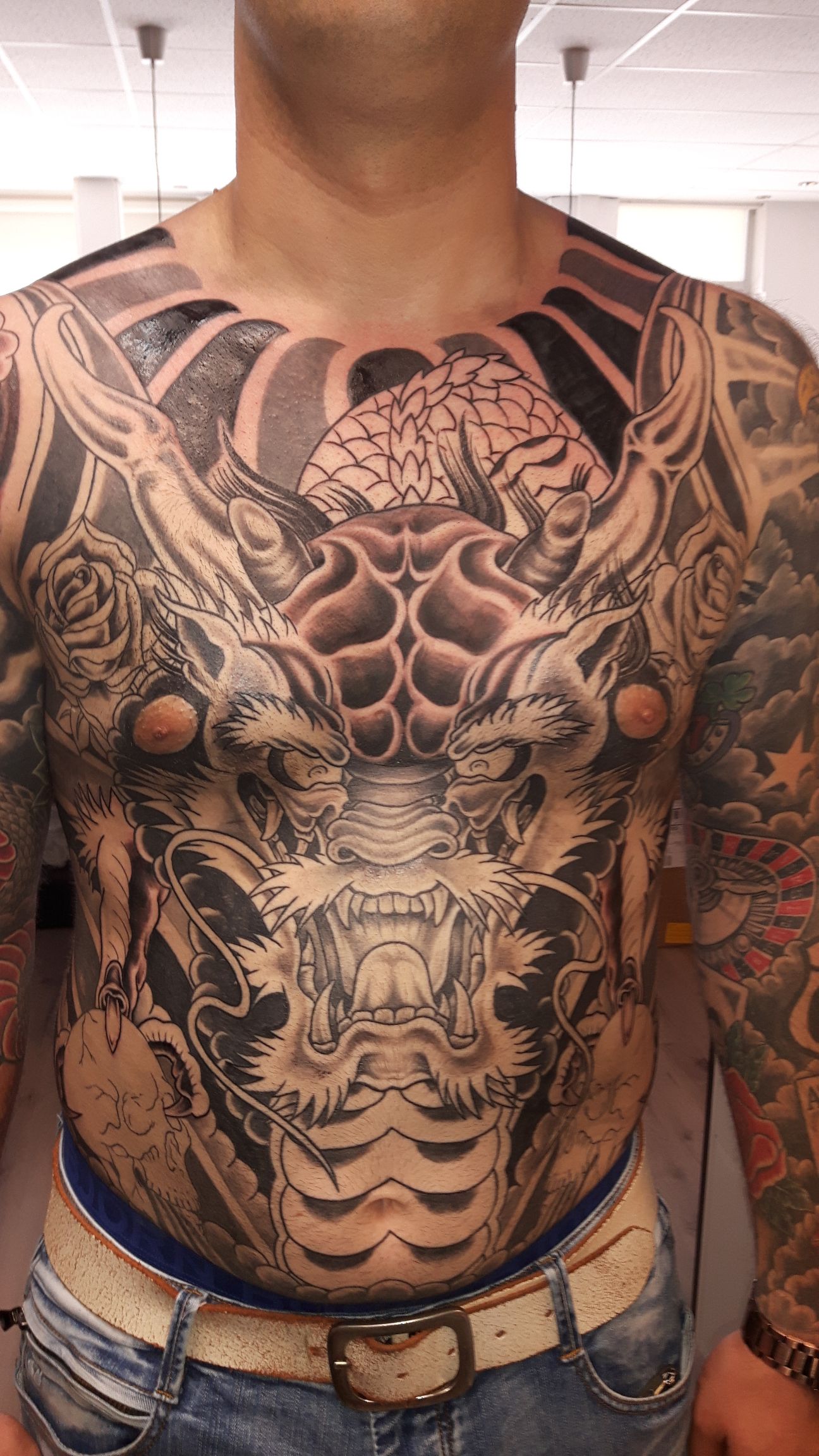 Grote Japanse draak tattoo op borst en buik, zwart-wit.