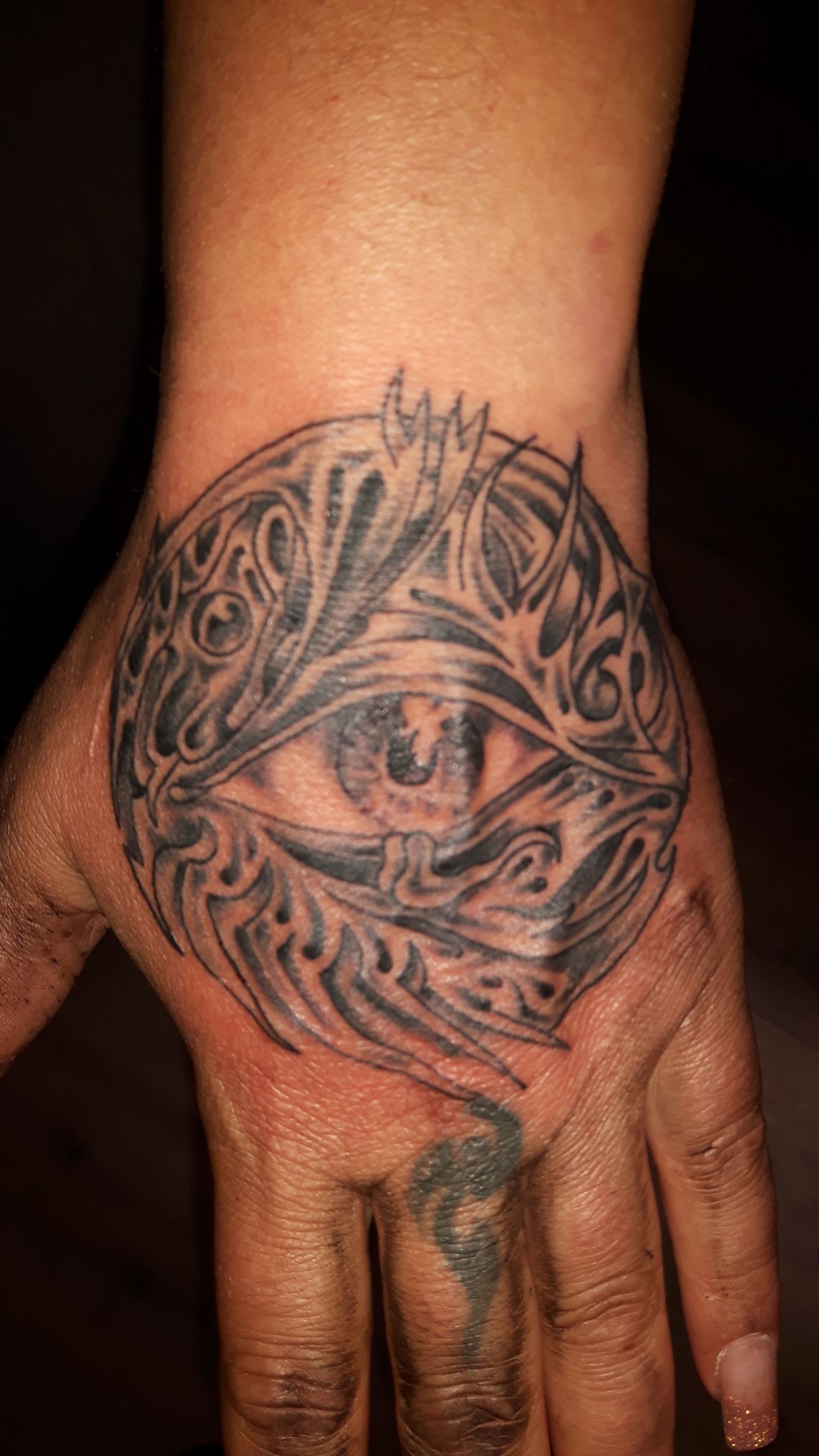 Zwart-wit tattoo van een oog in een cirkel met organische patronen op de hand.
