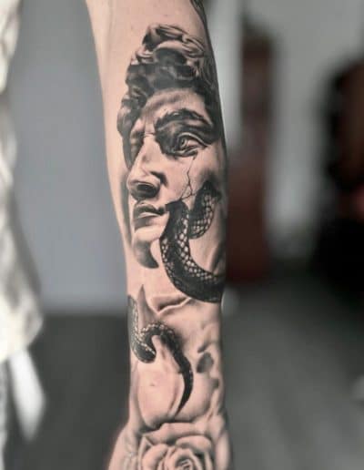 Realistisch standbeeldhoofd met slang en roos op onderarm.