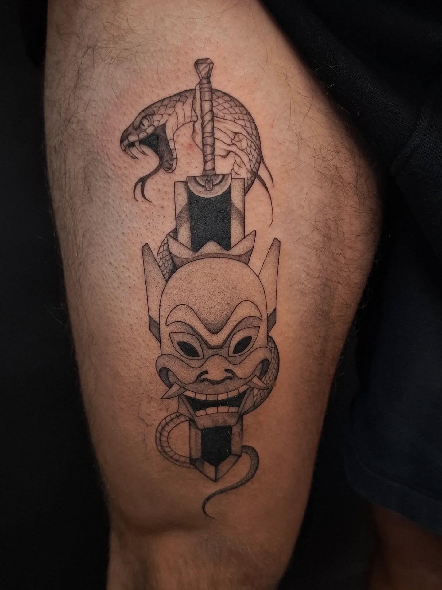 Blackwork tattoo van een zwaard met een slang en een masker.