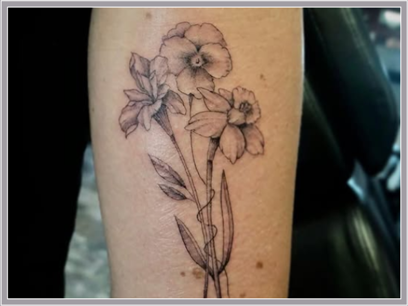 Fineline tattoo van een boeket met een viooltje, narcis en iris op de arm.