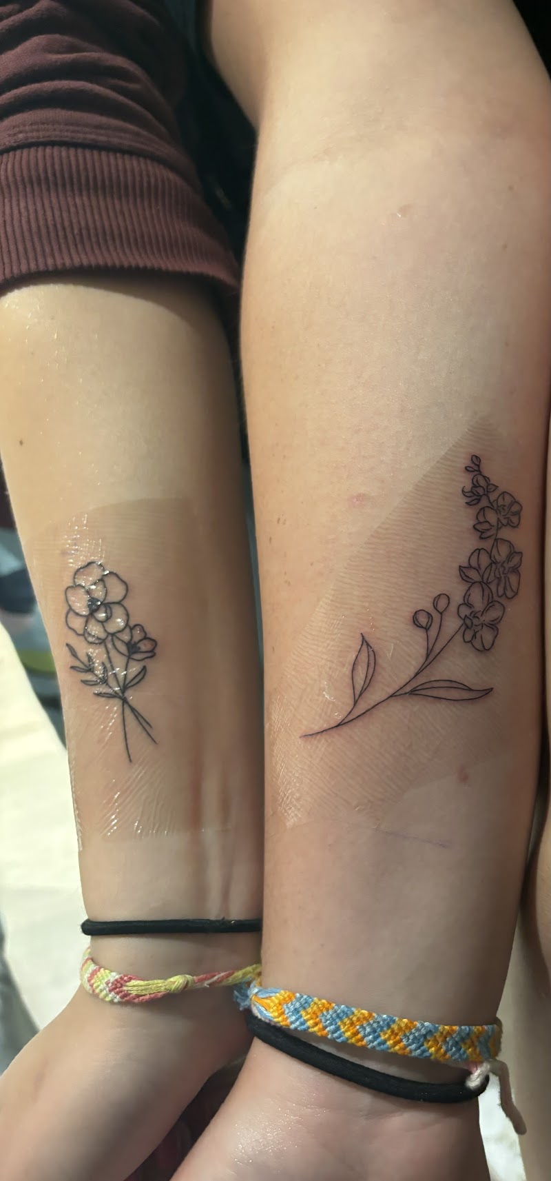 Twee fineline bloementattoos op onderarmen, één boeketje en één takje.