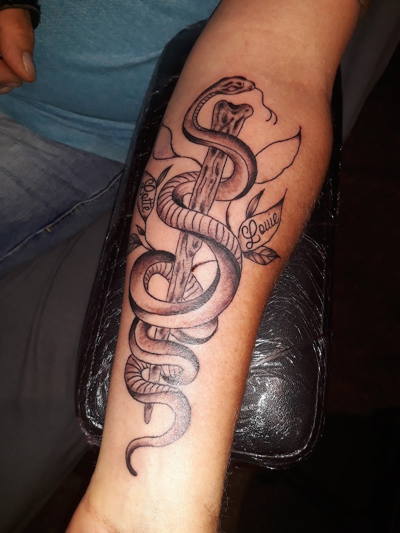 Zwart-wit tattoo van slang om bot met namen Lotte en Louie.