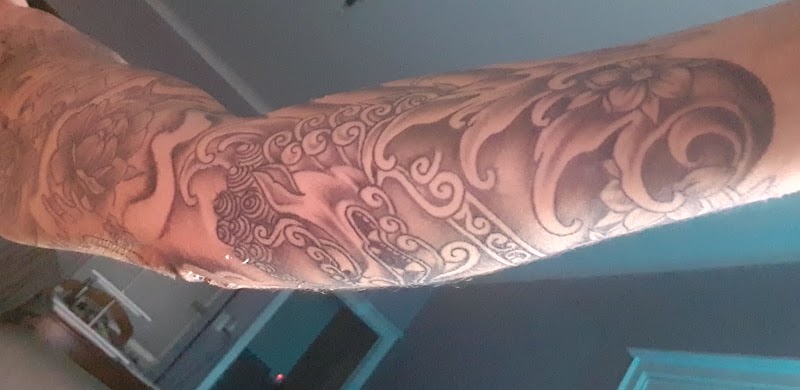 Japanse stijl tattoo met golven, bloemen en draak op arm.