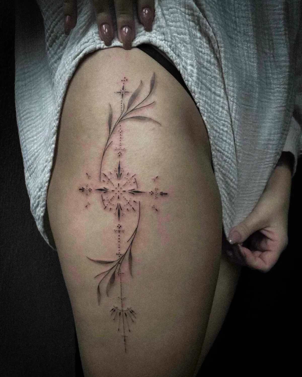 Fineline en dotwork tattoo met geometrische vormen en bladeren op het bovenbeen.