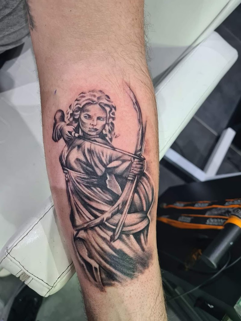 Zwart-wit tattoo van een vrouwelijke boogschutter op de onderarm.