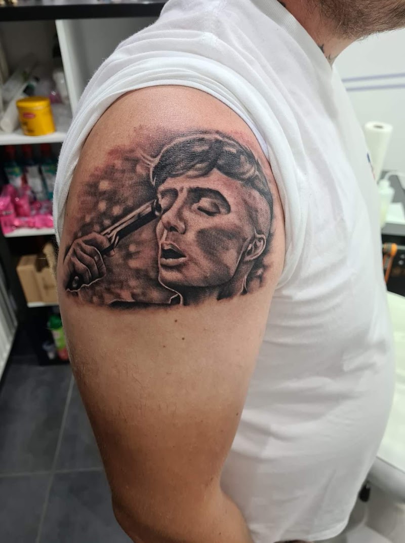 Realistisch portret van Tommy Shelby (Peaky Blinders) met pistool op bovenarm.