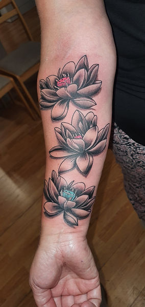 Drie lotusbloemen in zwart-wit met gekleurde harten op de onderarm.