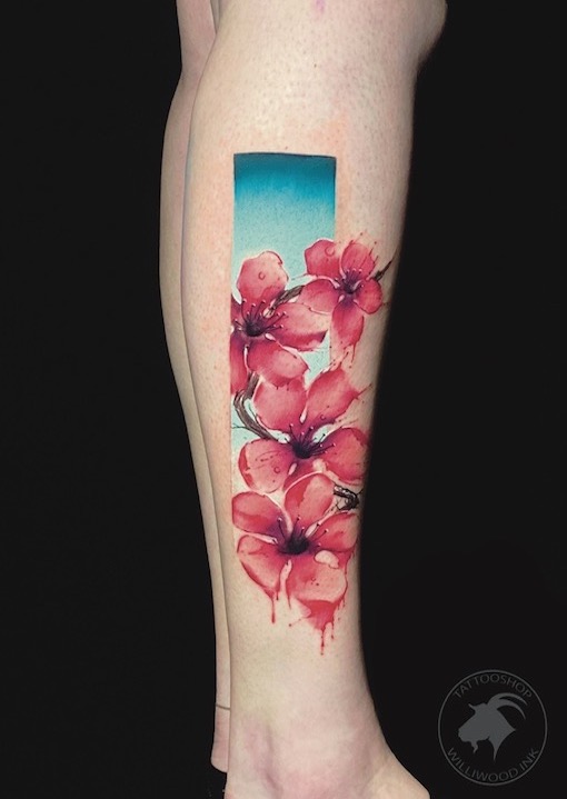 Aquarel kersenbloesem tattoo in een rechthoekig kader op het onderbeen.