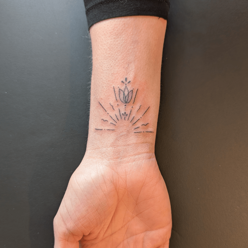 Minimalistische lotus met zonnestralen op de pols.