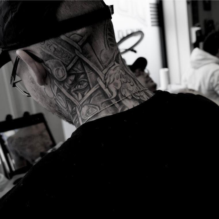 Grote zwart-wit nek tattoo met gedetailleerde architectuur en een oog.