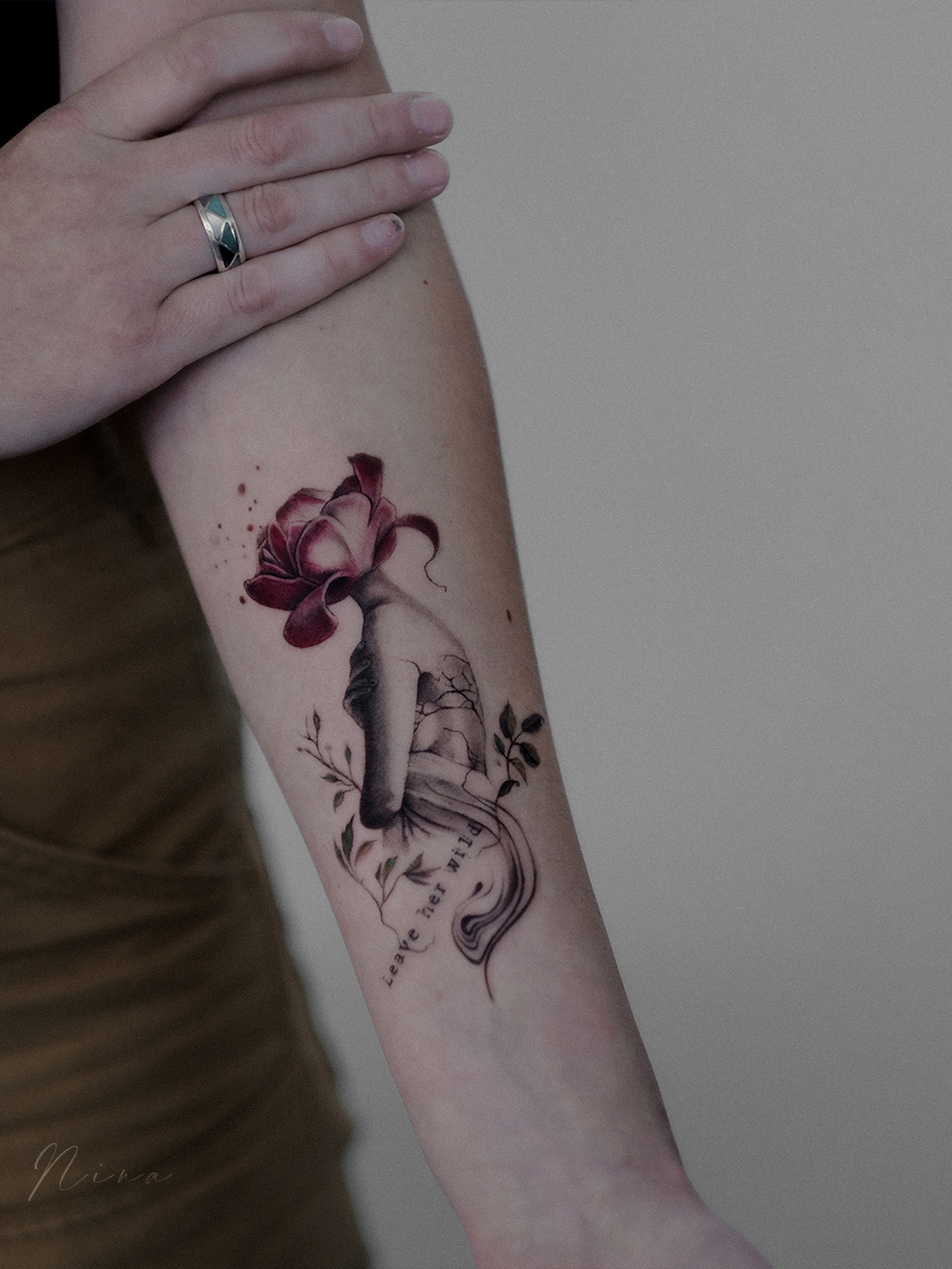 Illustratieve tattoo van een hand die een bloem wordt, met tekst 'Leave her wild'.