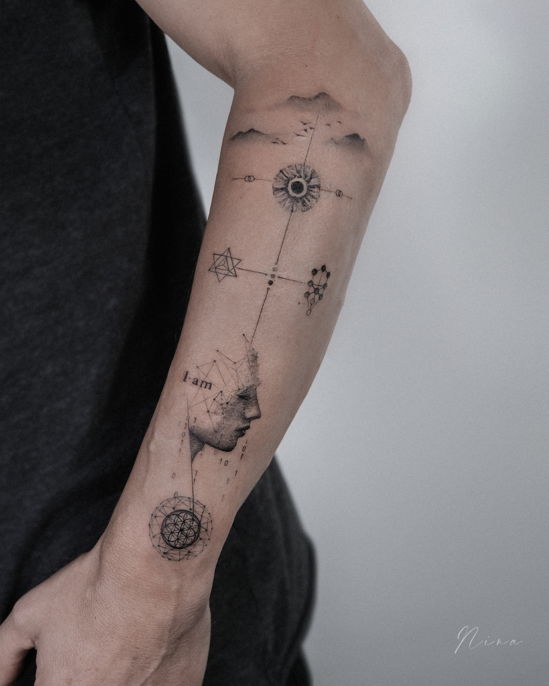 Complexe fineline tattoo met portret, geometrie en tekst op onderarm.