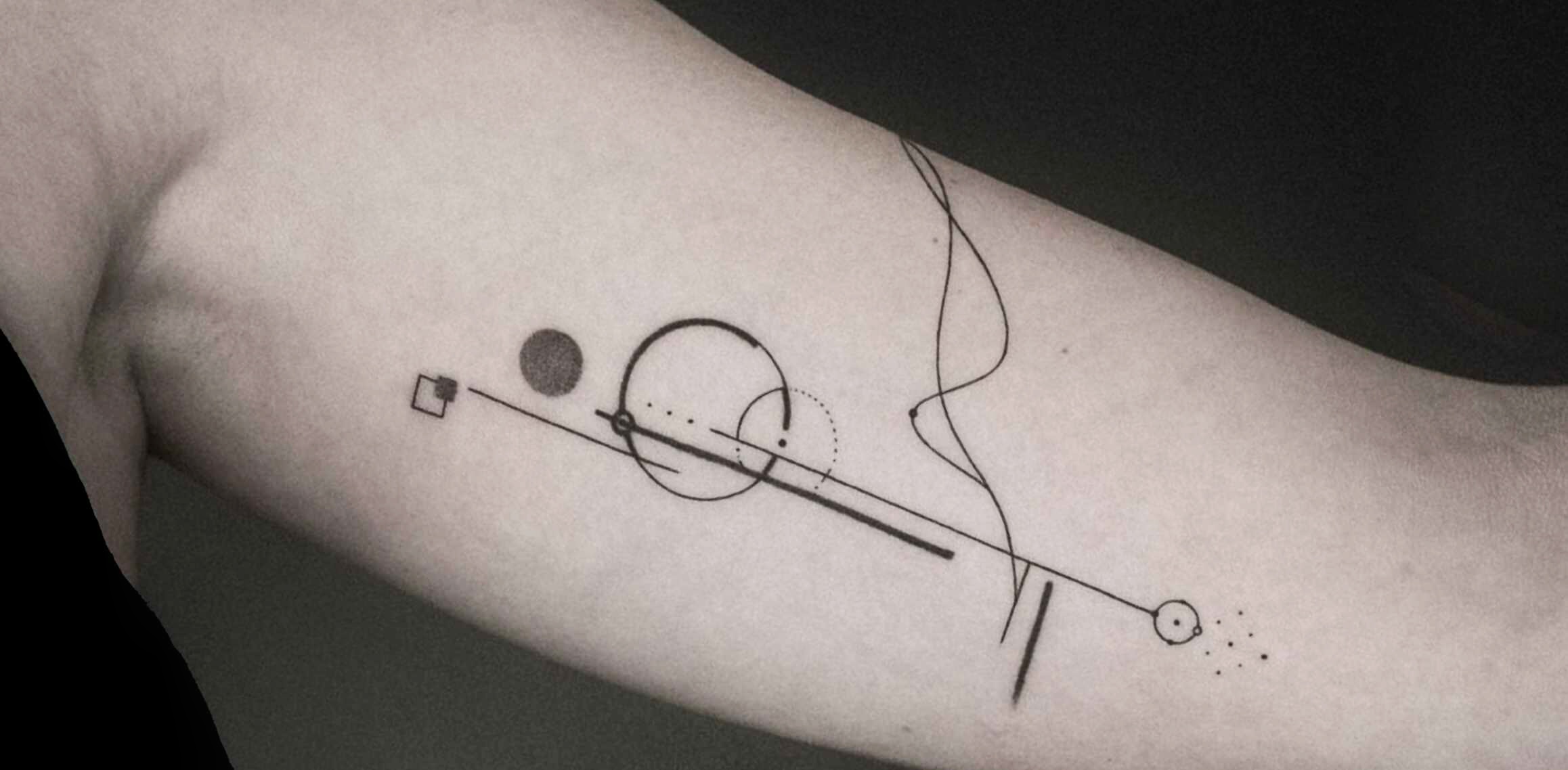 Minimalistische geometrische tattoo met lijnen en cirkels op de bovenarm.