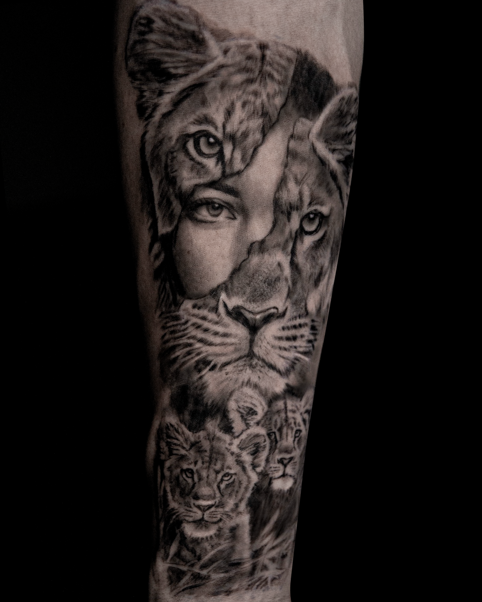 Realistische tattoo van een leeuwin, welpen en een vrouwengezicht.