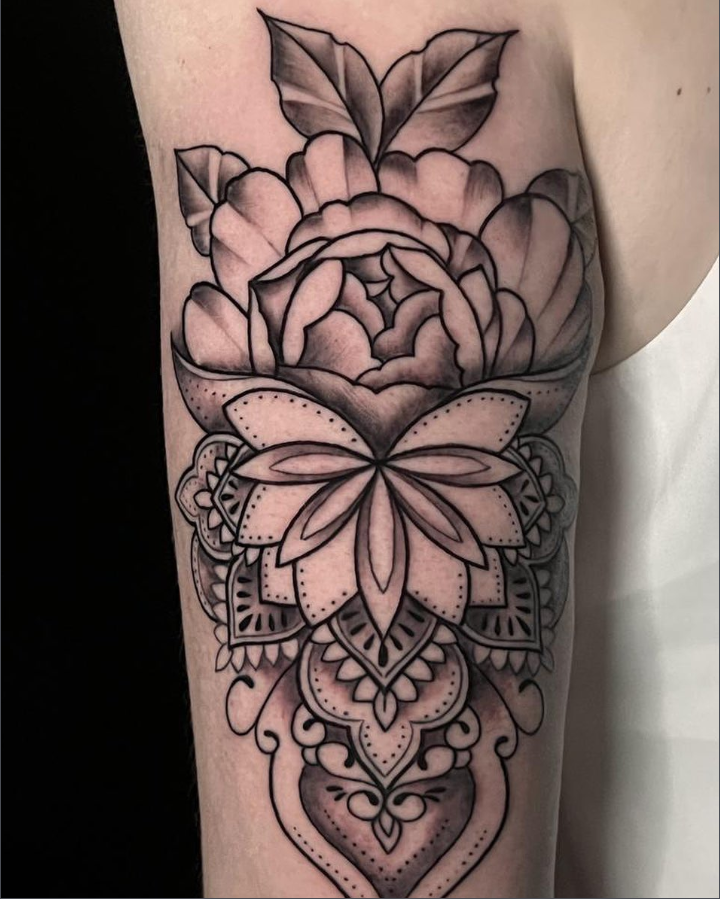 Zwart-wit tattoo van een pioenroos met een mandala patroon eronder.