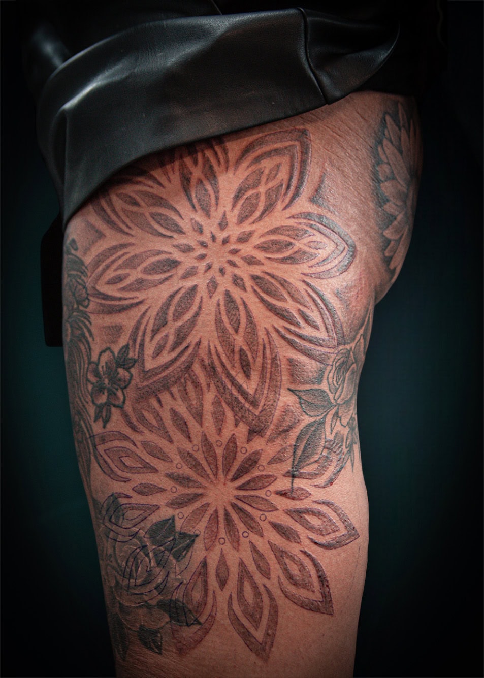 Grote mandala's en bloemen op bovenbeen.