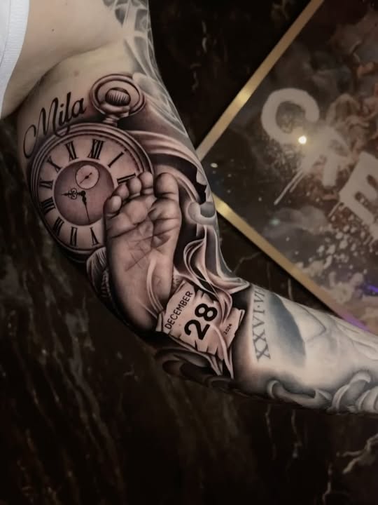 Realistische tattoo van babyvoetje, klok, kalender en naam 'Mila'.