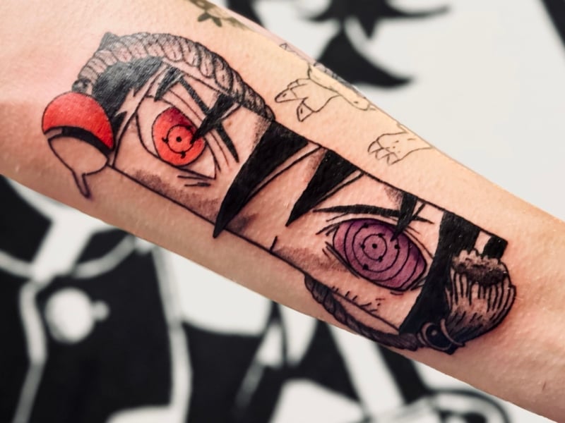 Anime tattoo van Sasuke's Sharingan en Rinnegan ogen op onderarm.