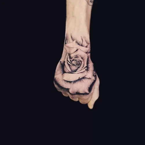 Realistische zwart-wit roos tattoo op de hand.