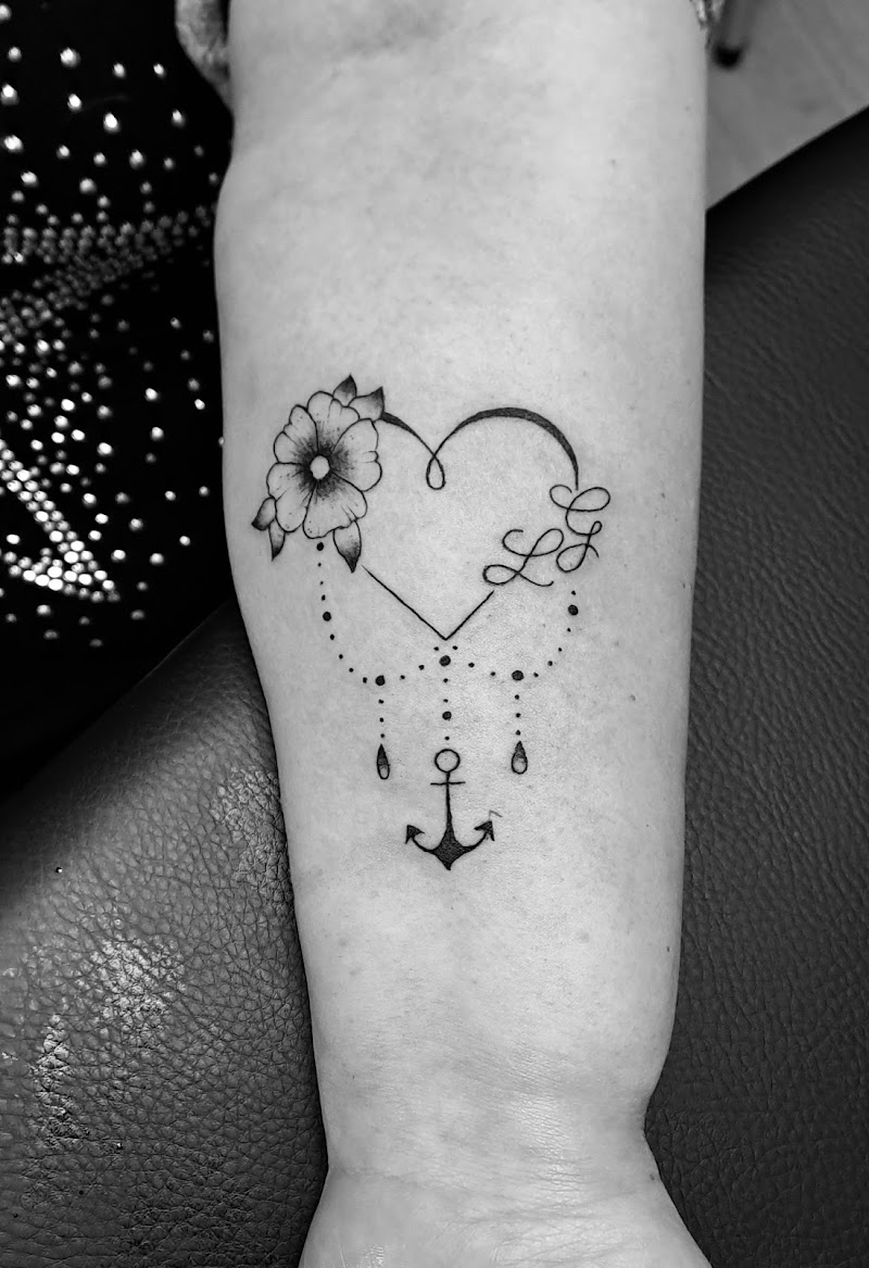 Fineline tattoo van een hart met bloem, initialen 'LG' en een anker.