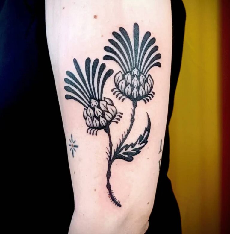 Zwartwerk tattoo van twee distels op de bovenarm.