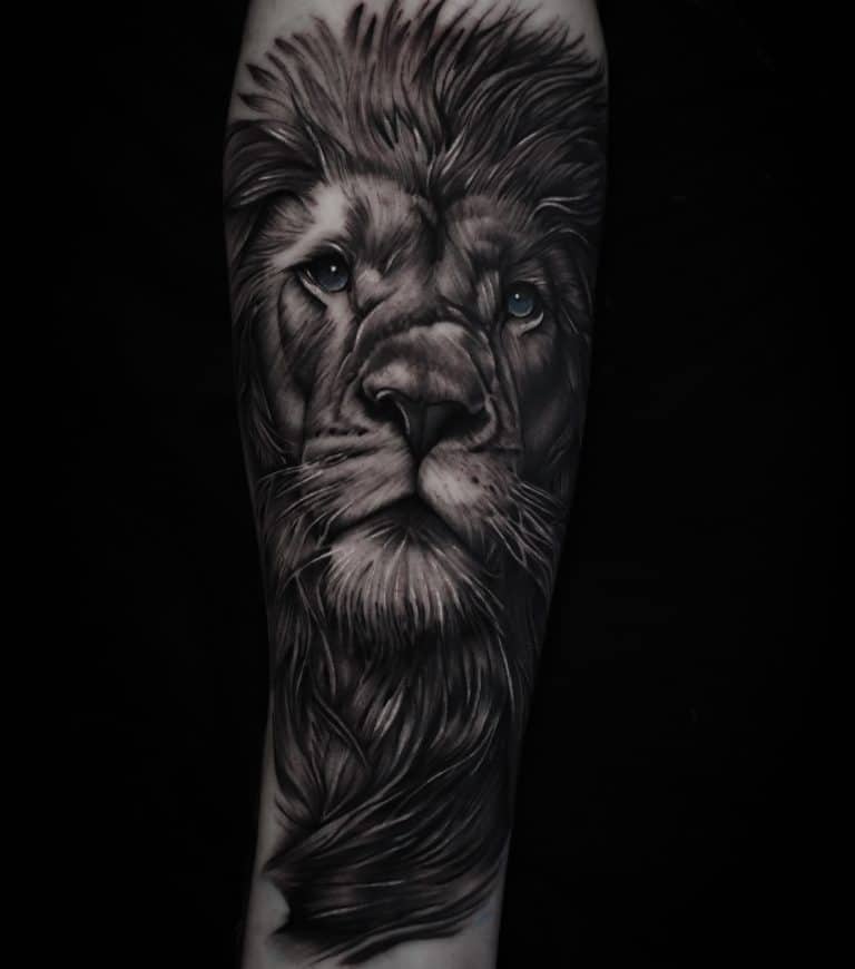 Realistische leeuwenkop met blauwe ogen op een arm.